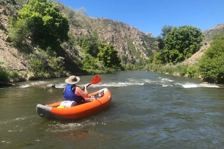 a man kayaking on the river in an inflatable kayak