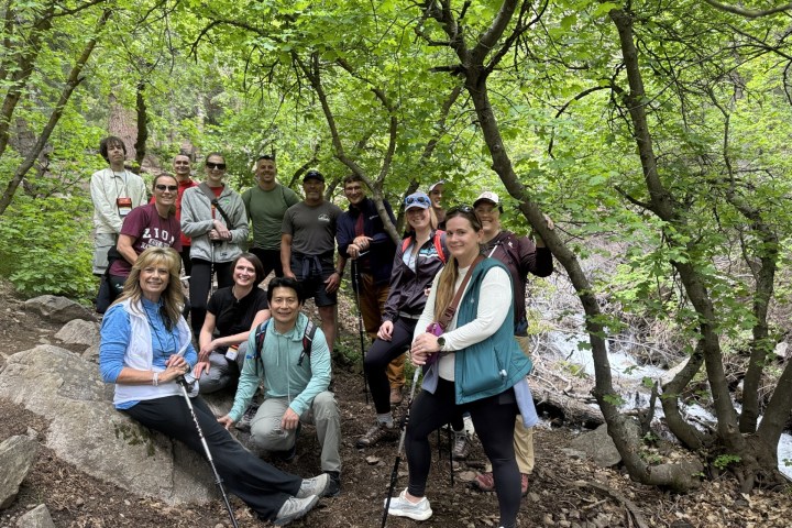 Group of hikers posing in a forest with green foliage.